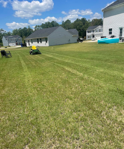 A yard with a lawn mower and a house in the background